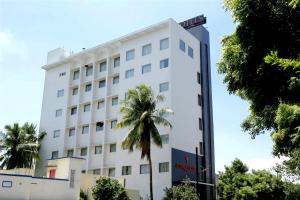a white building with a palm tree in front of it at Astoria Hotels Madurai in Madurai