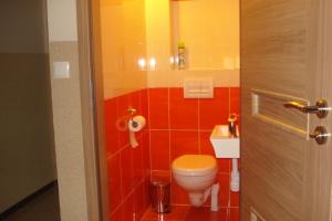 a bathroom with a toilet and red tiles at Kwatera Na Rogu in Augustów