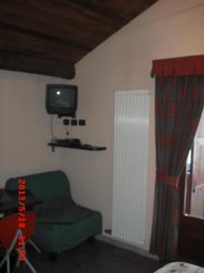 ein Wohnzimmer mit einem grünen Stuhl und einem TV in der Unterkunft Lauson in Cogne