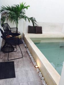 a swimming pool in a building with chairs and a couch at La casa de Leslie - Apartment 2 in Mérida