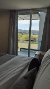 sypialnia z łóżkiem i dużym oknem w obiekcie suites del champaqui w mieście Villa General Belgrano