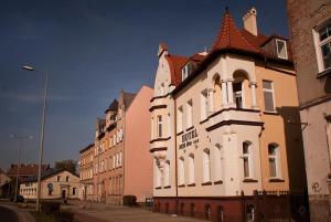 um grande edifício branco com uma torre de relógio numa rua em Hotel MCM Plus em Gorzów Wielkopolski