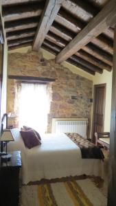 una camera da letto con un letto e un muro di pietra di La Casa de Piedra de la Aldea ad Aldea del Pinar