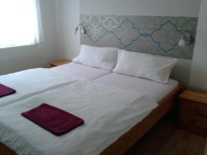 Una cama con sábanas blancas y toallas púrpuras. en Janus Apartman en Sárvár