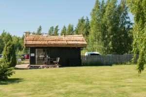 une petite cabane avec un toit de chaume dans une cour dans l'établissement Peterzens Boathouse, à Laupunen