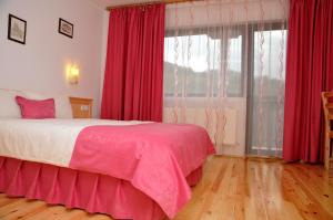 a bedroom with a bed with red curtains and a window at Family Hotel and Restaurant Plamena in Oreshak