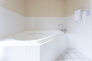 uma banheira branca numa casa de banho com azulejos brancos em Historic Shipping Office - Akaroa em Akaroa