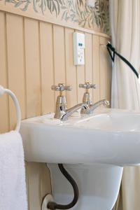 a white sink in a bathroom with a shower curtain at Historic Shipping Office - Akaroa in Akaroa
