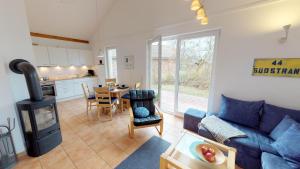 ein Wohnzimmer mit einem blauen Sofa und einem Herd in der Unterkunft Feriendorf Südstrand Haus 44 in Pelzerhaken
