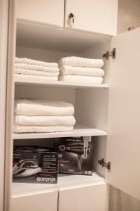 a closet with white towels and a box at Pupin Palace Apartments in Novi Sad