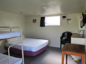een kleine kamer met 2 stapelbedden en een bureau bij Dunedin Holiday Park in Dunedin