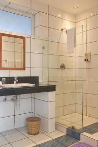 a bathroom with a shower and a sink and a mirror at Stylish Beachfront Apartment Mombasa King Sized bed in Mombasa