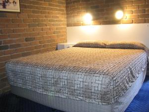 a bedroom with a bed with a brick wall at Cattleman's Rest Motor Inn in Charters Towers