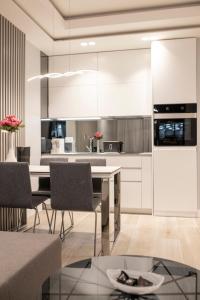a kitchen with white cabinets and a dining table at Pupin Palace Apartments in Novi Sad