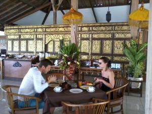a man and woman sitting at a table in a restaurant at Gazebo Beach Hotel in Sanur