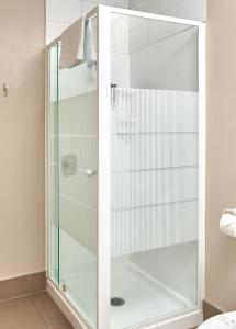 a shower with glass doors in a bathroom at Barringtons Motor Lodge in Whakatane