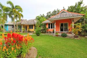 a house with colorful flowers in the yard at Maikhao Home Garden Bungalow in Mai Khao Beach
