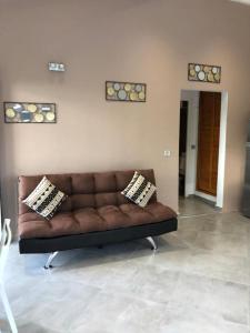 Sofá marrón en la sala de estar con 2 almohadas en Chez BIBI, en Grand-Bourg