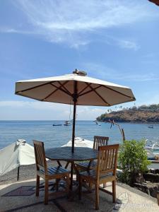 - une table et des chaises avec un parasol sur la plage dans l'établissement Sunrise Cafe Bungalows, à Amed