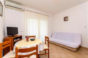een kamer met een tafel, een bank en een televisie bij Apartments Luka in Trogir