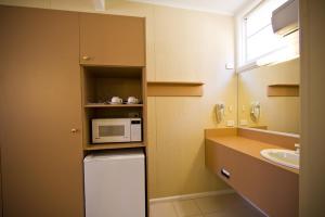a kitchen with a sink, microwave and refrigerator at Parkville Motel in Melbourne