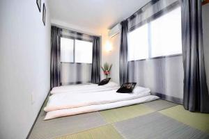1 dormitorio con 2 camas frente a una ventana en 大阪之家 心斋桥难波附近4室一厅整套房子4 可接送机场, en Osaka