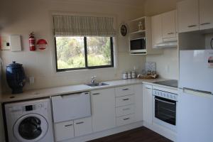 a white kitchen with a sink and a dishwasher at Grace Cottages in Uralla