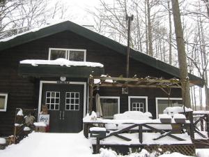 a log cabin with snow on the front of it at Lodge Stack Point in Narusawa