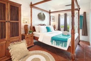 a bedroom with a canopy bed and a chair at Kerang Bingin Beach Villa in Uluwatu
