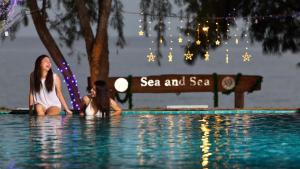 Sea and Sea Villa Sangaroon في Ban Nam Tok: جلسه امرأتين في مسبح في منتجع