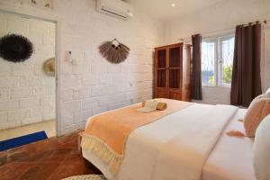 ein großes weißes Bett in einem Zimmer mit Fenster in der Unterkunft Kerang Bingin Beach Villa in Uluwatu