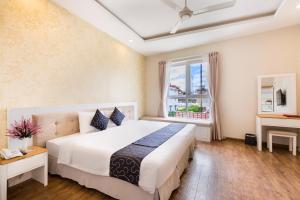 - une chambre avec un grand lit blanc et une fenêtre dans l'établissement Capital O 585 Saigon Book Da Lat Hotel, à Đà Lạt