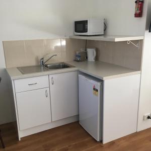 a small kitchen with a sink and a microwave at Forster and Wallis Lake Motel in Forster