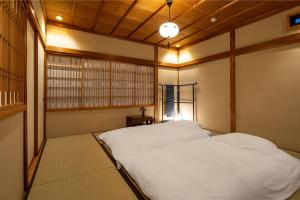 a bedroom with a white bed in a room at Kurohoro Machiya House in Kanazawa