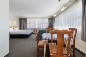 a hotel room with a bed and a table and chairs at Thermal Oak Motel in Rotorua