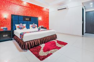 een slaapkamer met een groot bed met een rode muur bij FabHotel Royal Mirage With Pool & GYM, Candolim Beach in Candolim