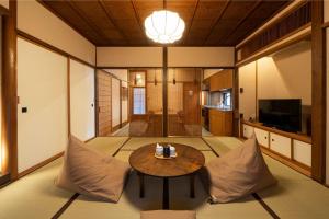 a living room with a table and a kitchen at Kurohoro Machiya House in Kanazawa