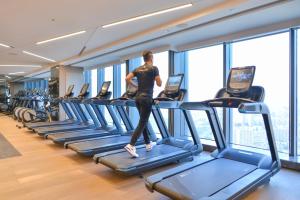 un homme qui marche sur un tapis de course dans une salle de sport dans l'établissement Pullman Huizhou Kaisa, à Huizhou