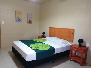 - une chambre dotée d'un grand lit avec des draps verts dans l'établissement Transit Motel, à Mulifanua