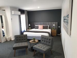 een hotelkamer met een bed en twee stoelen bij Twofold Bay Motor Inn in Eden