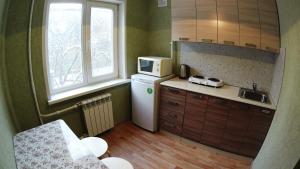 a small kitchen with a refrigerator and a microwave at Apartments on Prospekt Dimitrova in Novosibirsk