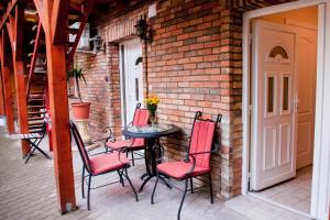 a patio with a table and chairs and a brick wall at King Arthur Panzió in Baja