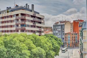 ein hohes Gebäude in einer Stadt mit Bäumen und Gebäuden in der Unterkunft Pensión Mendi in Pamplona