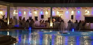 a pool with a fountain in front of a wedding party at Golden Sun Hotel in Stelida