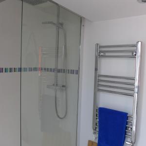 a glass shower in a bathroom with a blue towel at Sea Glimpses with garden, beachhut, parking in Broadstairs +38 photos