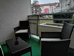 艾森斯塔特的住宿－Ferienwohnung Dado，阳台配有两把椅子和一张桌子,铺有绿色地板。