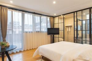 a bedroom with a white bed and a television at Wander Hostel in Haikou