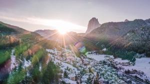 an aerial view of a town in the mountains with the sun setting at AppartChalet LA RONDULA - 100m from Seceda in Ortisei