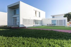 una casa bianca con un cortile verde di Santa Cruz Ocean View Villa a Bombardeira