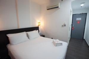 a hotel room with a white bed and white walls at Tune Hotel - Waterfront Kuching in Kuching